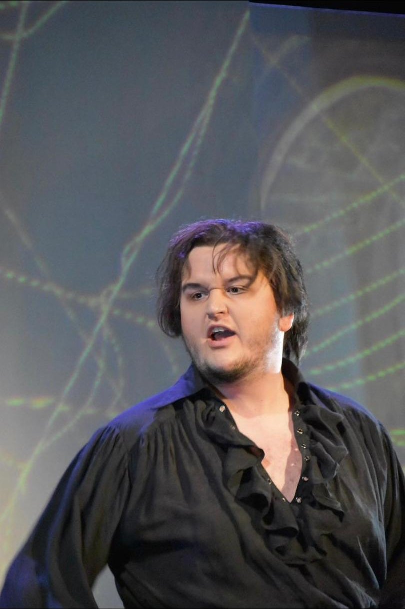 Rhys Stermer in a staged performance with projected scenery.